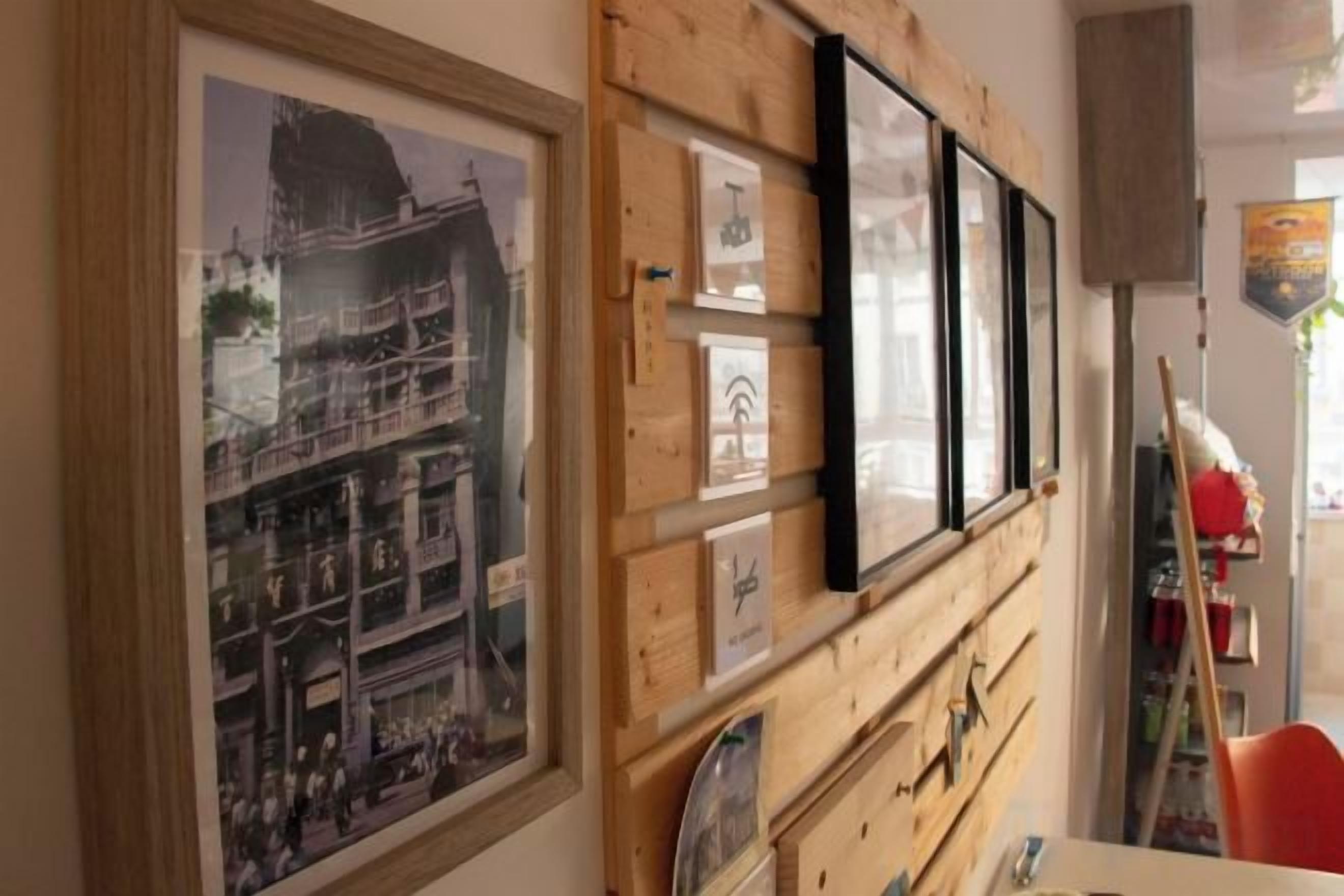 A wall with framed pictures and a wooden panel.