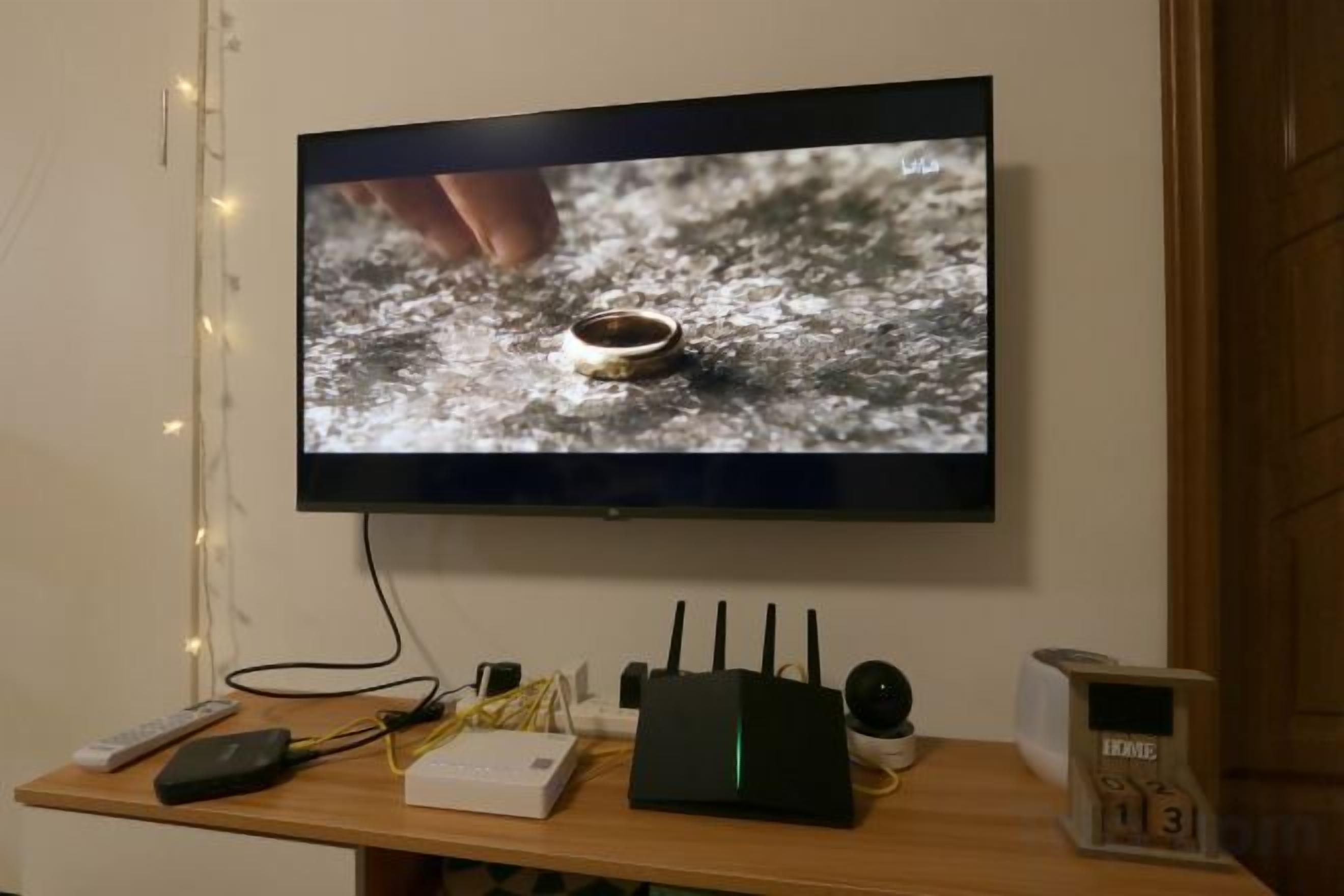 Un televisor montado en la pared mostrando un primer plano de un anillo sobre una superficie con textura.