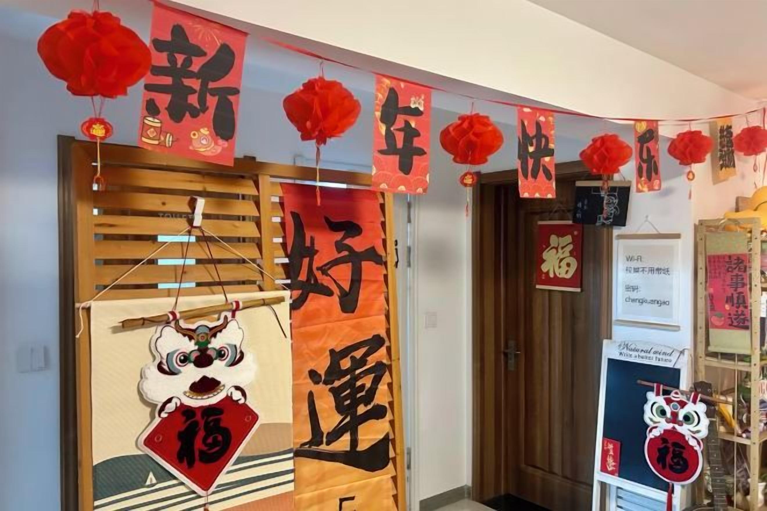 Een kamer met een traditionele Chinese deur, rode decoraties en een bord met Chinese karakters.