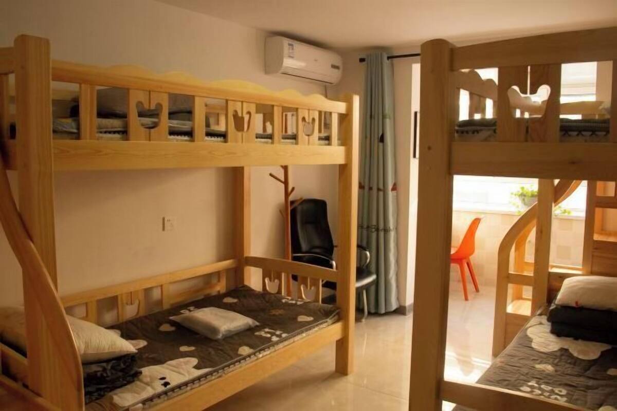 Une chambre avec un lit superposé, un bureau, une chaise et un appareil de climatisation.