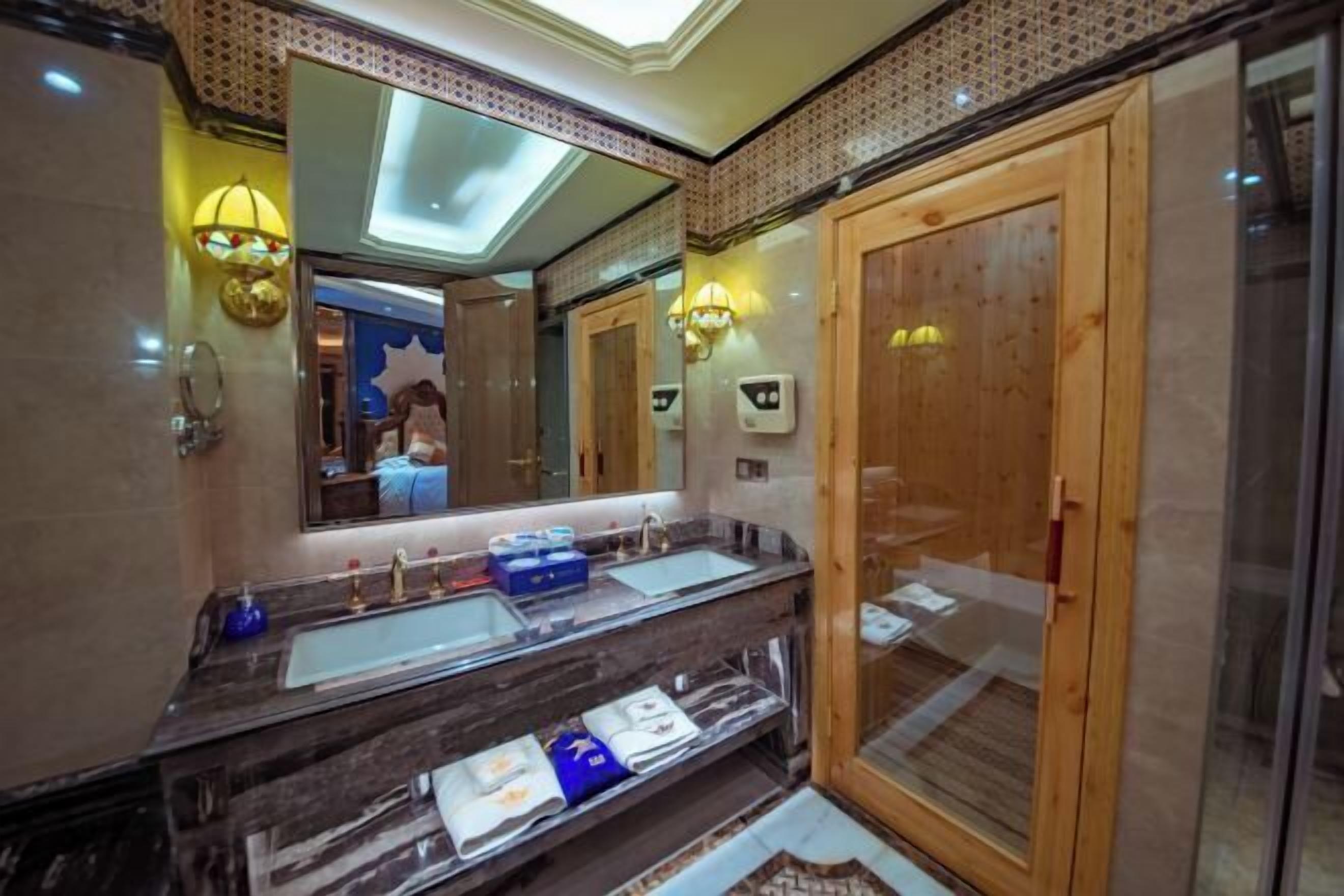 A modern bathroom with a large mirror, dual sinks, and a wooden door.