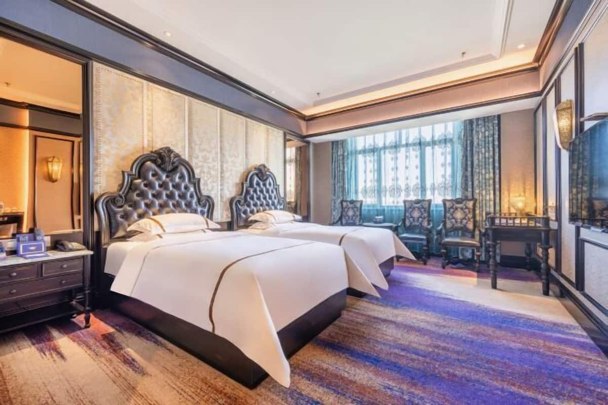 A hotel room with a large bed, a desk, and a chair.