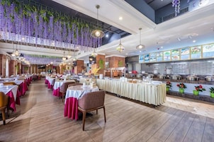 A restaurant with multiple dining tables, hanging plants, and a kitchen area.