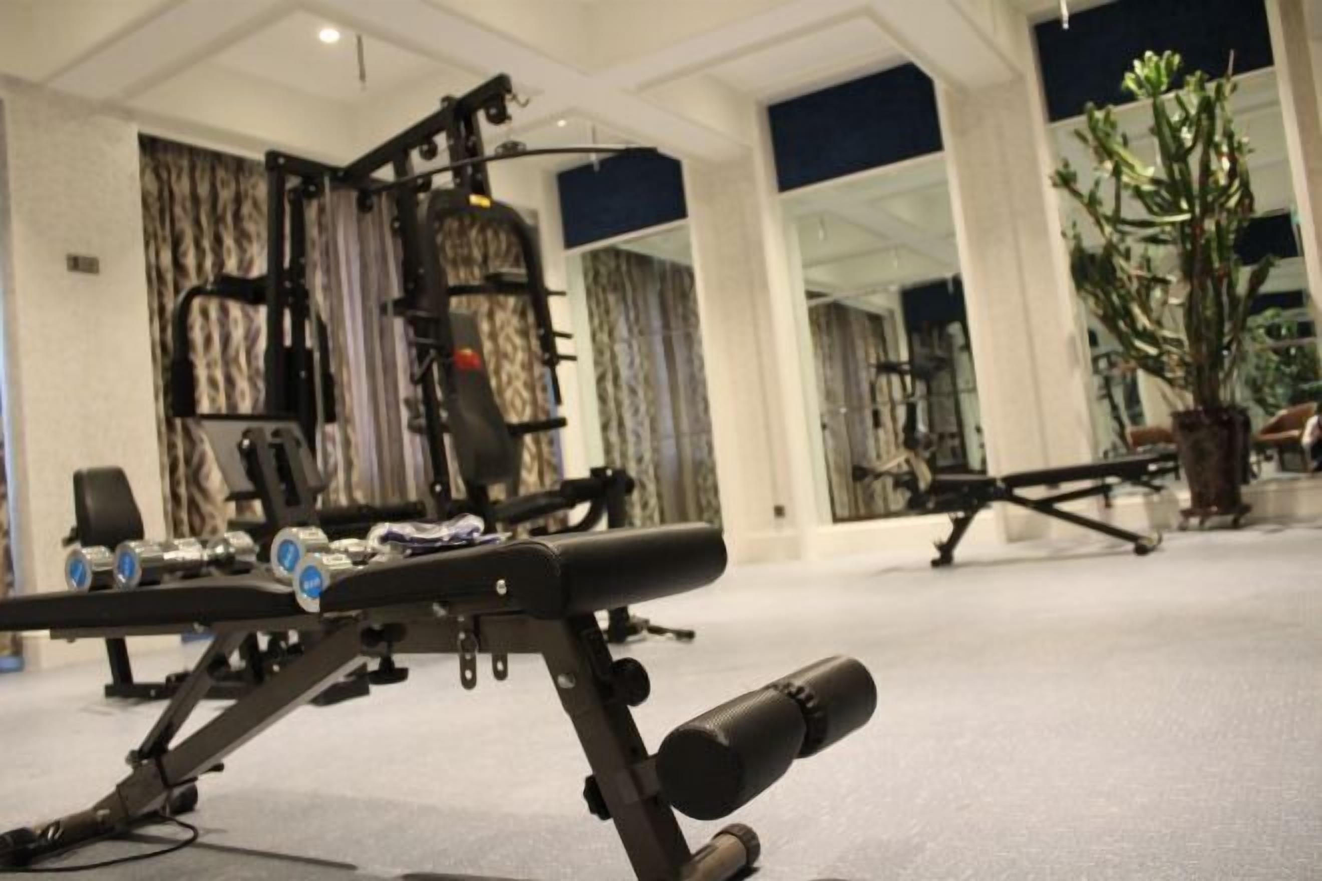 Une salle de sport équipée de matériel d’exercice, notamment un banc de développé couché et des haltères.