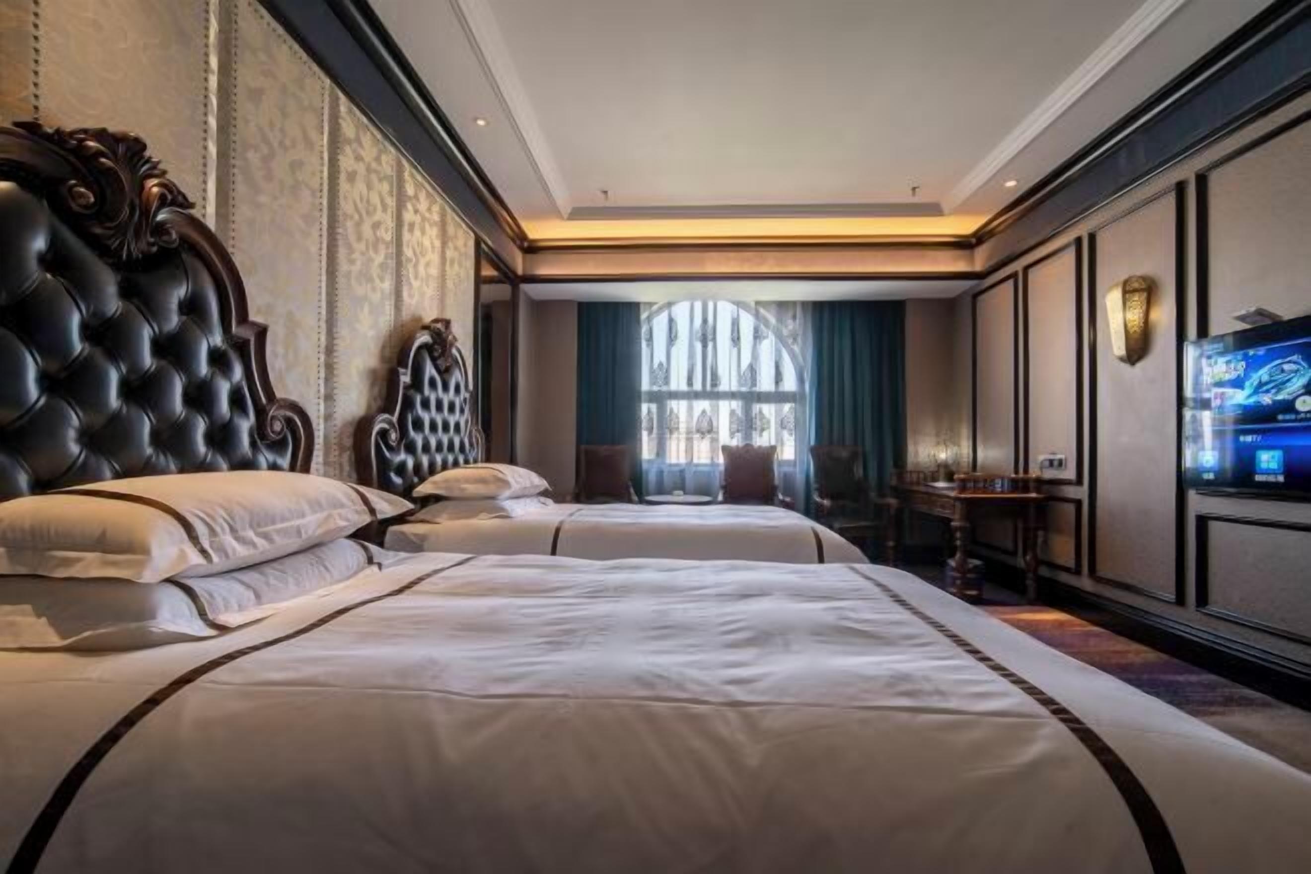 Une chambre d’hôtel avec deux grands lits, une télévision et une fenêtre avec des rideaux.