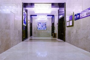 A hallway with a chandelier, a large abstract painting, and a poster on the wall. - Qingzhu Hotel · Junxi Select (Chongqing)