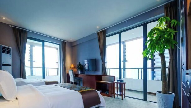 Ein Hotelzimmer mit Bett, Schreibtisch, Fernseher und großem Fenster.