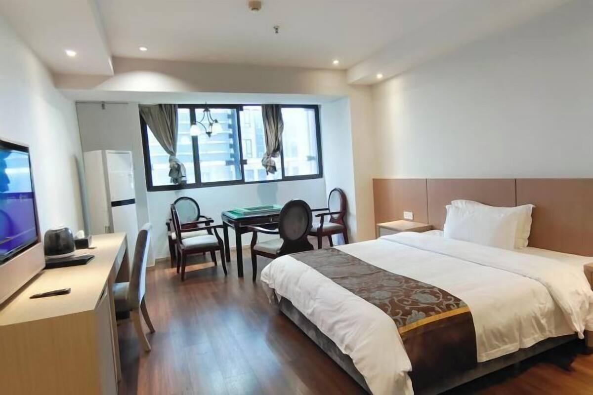 A hotel room with a bed, desk, chair, and a television.