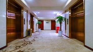 Ein Hotelkorridor mit Teppichboden, Holztüren und Blumentöpfen.