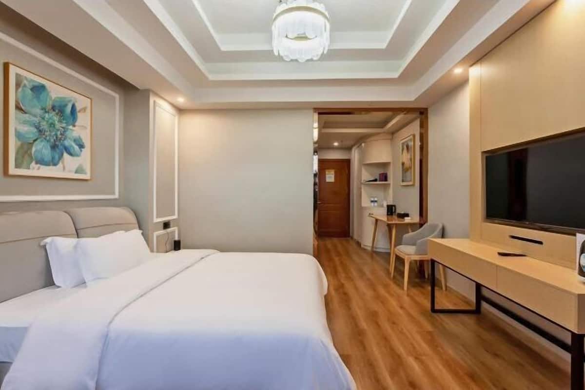 A hotel room with a bed, a TV, a desk, and a chair.