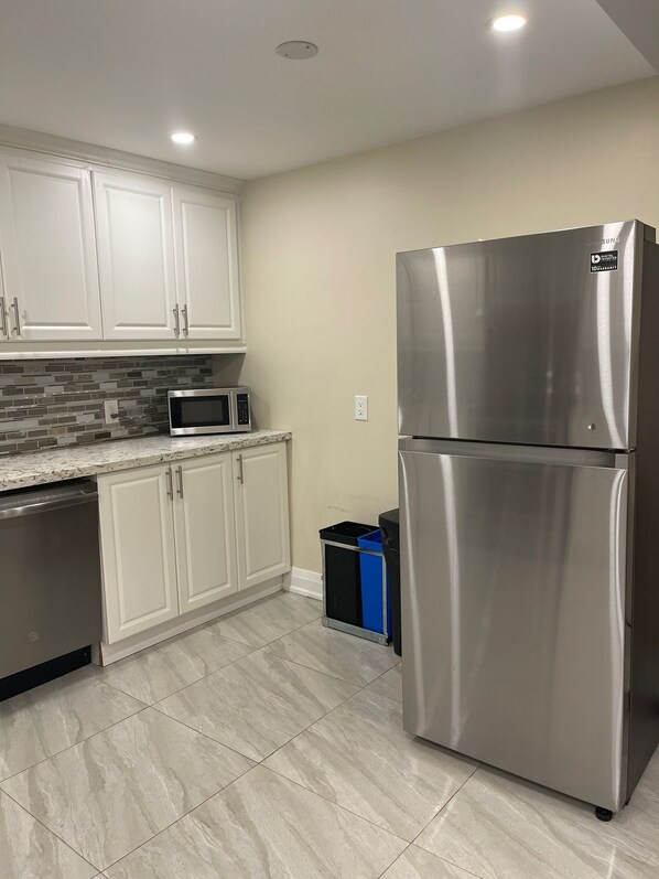 Una cocina moderna con armarios blancos, un refrigerador de acero inoxidable, un microondas y un lavavajillas.