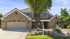 A two-story house with a garage, a stone facade, and a well-maintained lawn. - Hot Tub Game Room. Sleeps 17. You Tube TV. 20 minutes to Zions Natl Park (La Verkin)