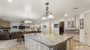 A spacious kitchen with granite countertops, white cabinetry, and a large island. There is a dining area with leather seating and a fireplace. - Hot Tub Game Room. Sleeps 17. You Tube TV. 20 minutes to Zions Natl Park (La Verkin)