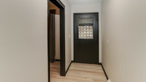A narrow hallway with a dark door at the end, light-colored walls, and a wooden floor. - Amazing East Side 3BR 2BA Wifi SMRT TV (Wichita)
