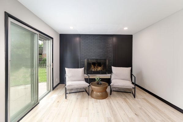 A modern living room with a fireplace, two armchairs, and a coffee table.