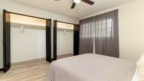 A bedroom with a bed, a ceiling fan, a wardrobe, and a window with curtains. - Amazing East Side 3BR 2BA Wifi SMRT TV (Wichita)