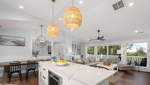 A modern kitchen with white cabinetry, a large island, and pendant lighting. - Last-Minute! Soundfront, Pool, Hot Tub, Elevator, Renowned Currituck Club Access (Corolla)