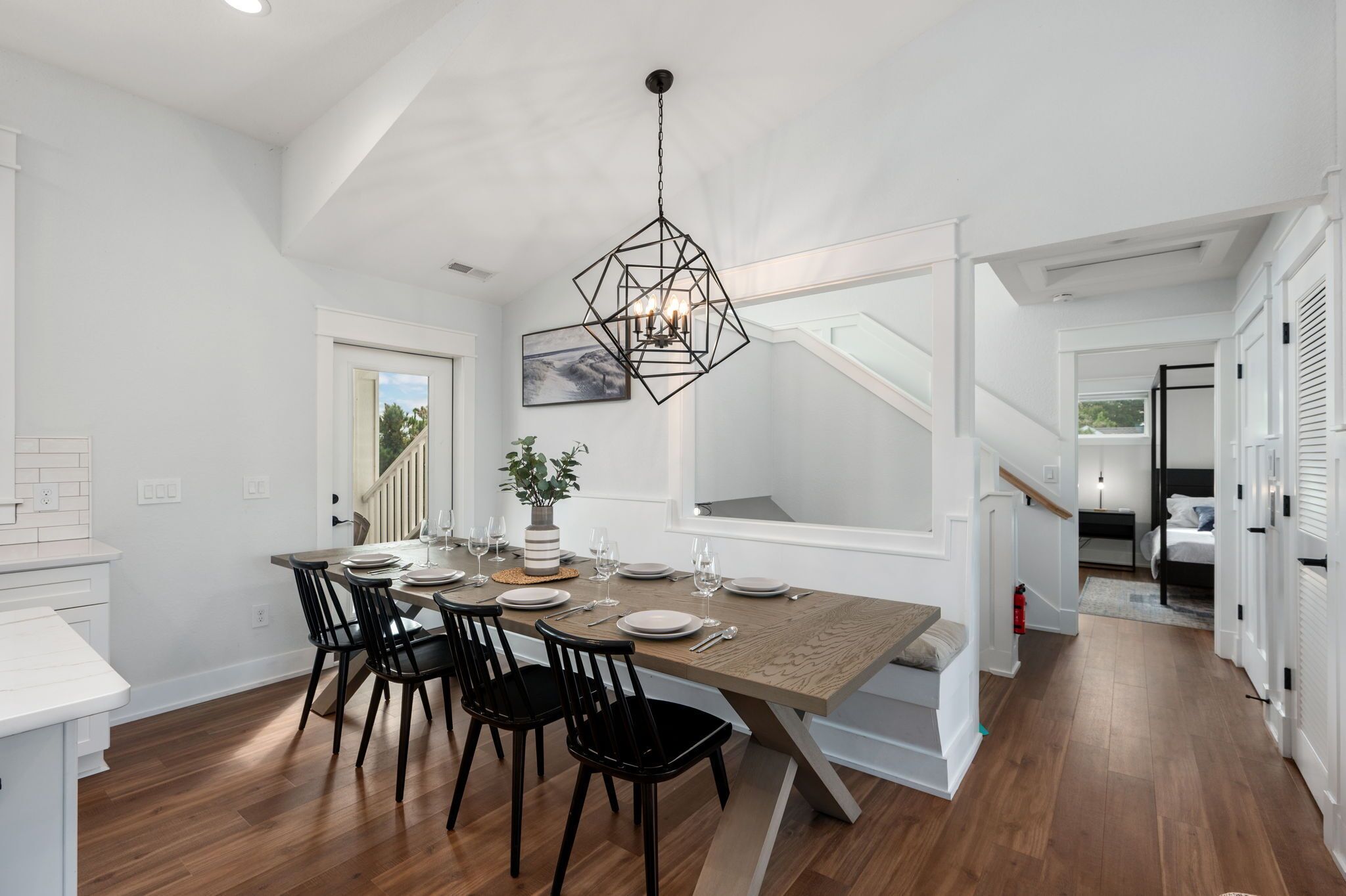 Un comedor moderno con una mesa de madera, sillas negras y una lámpara colgante de diseño geométrico.