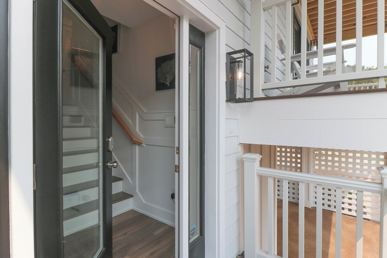 A staircase leading to a second-floor balcony with a white railing and a wooden deck.