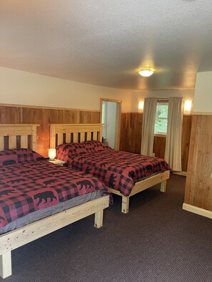 A room with two wooden beds, a carpeted floor, and wooden paneling on the walls. - Sportsmen Motel (Dorchester)