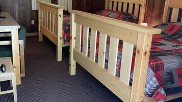 A room with two wooden beds, a desk, and a chair.