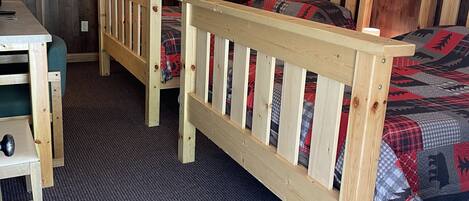 Une chambre avec deux lits en bois, un bureau et une chaise.