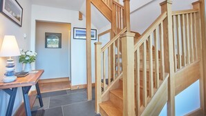 Un escalier en bois avec une rampe, un bureau avec une lampe et des tableaux encadrés accrochés au mur.
