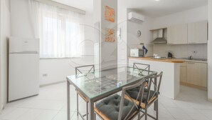 Une cuisine moderne avec une table à manger en verre, des meubles blancs et une cuisinière intégrée.