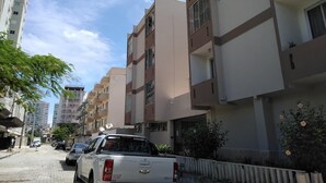 A residential street with multi-story buildings, parked cars, and a clear sky. - Itapema - Ap. Inteiro em Itapema Rua 129 B (Centro Itapema)