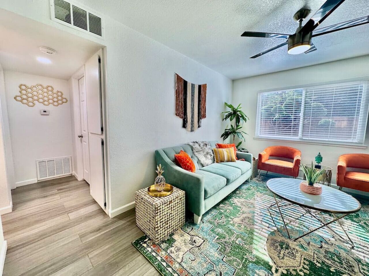 A living room with a sofa, two armchairs, a coffee table, and a patterned rug.