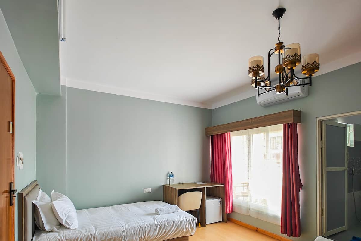 A bedroom with a bed, a desk, and a wardrobe.