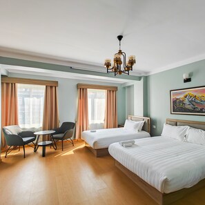 A hotel room with two beds, a desk, a chair, and a painting on the wall. - Boudha Apart Hotel (Kathmandu)