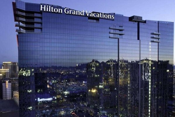 Standing tall, the Hilton Grand Vacations building features a sleek glass facade with the building's name prominently displayed at the top.