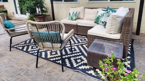A patio with wicker furniture, a patterned rug, and a potted plant. - Unique, private and central (Mililani)