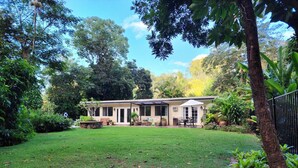 A house with a covered patio, a lawn, and surrounding trees. - Unique, private and central (Mililani)