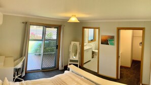 Ein Hotelzimmer mit Bett, Schreibtisch, Stuhl und Bad mit Spiegel, sowie einer Glastür zum Außenbereich.