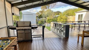 Eine Terrassenanlage im Freien mit Grill, Kicker und Tisch mit Metallkübeln.