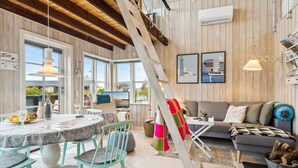 Ein gemütliches Wohnzimmer mit Holzboden, einem Essbereich mit rundem Tisch und Stühlen, einer Couch und einer Treppe.