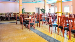 A spacious dining area with multiple tables and chairs, a central aisle, and a yellow and black striped floor. - 6A Resort and Hotels Owerri (Owerri)