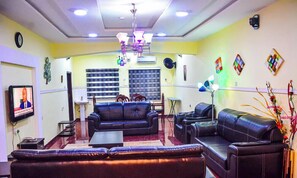 A living room with a sofa set, a TV, a chandelier, and decorative wall art.