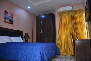 A bedroom with a bed, wardrobe, and an air conditioning unit.