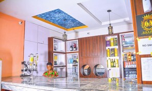 A bar area with a marble countertop, wooden cabinets, and a ceiling with a blue artwork. - 6A Resort and Hotels Owerri (Owerri)