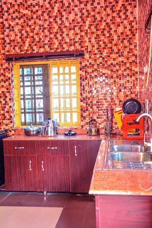 Una cocina con un salpicadero decorativo, armarios de madera, un fregadero y una ventana con persianas.