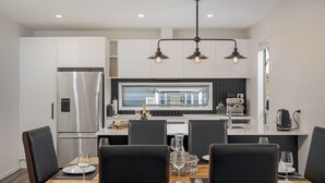 A modern kitchen with a dining area. - A Sunshine Retreat - Pauanui Holiday Home (Pauanui)