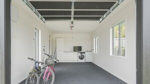 A laundry room with a washing machine, dryer, and a television on a counter. - A Sunshine Retreat - Pauanui Holiday Home (Pauanui)