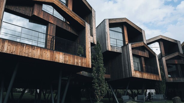 A modern architectural structure with multiple levels and large windows, supported by metal beams. - FLORIS GREEN SUITES (Castelrotto)