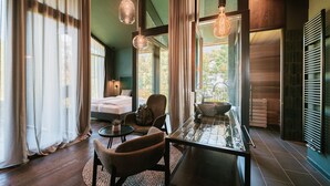 A modern room with a glass dining table, two chairs, a sofa, and a bed. - FLORIS GREEN SUITES (Castelrotto)