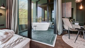 A modern bathroom with a freestanding bathtub, a shower, and a glass-enclosed balcony with a view of the outdoors. - FLORIS GREEN SUITES (Castelrotto)