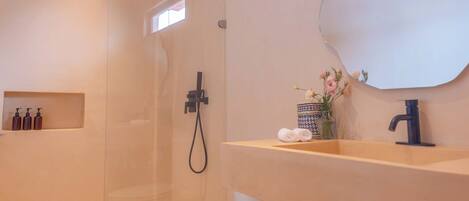 A modern bathroom with a glass-enclosed shower, a white toilet, a wooden vanity with a sink, and a mirror.