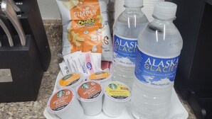 A tray with breakfast items including Cheetos Puffs, Starbucks coffee, and Alaskan Glacier water bottles.